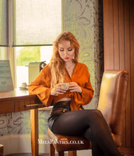 Load image into Gallery viewer, Melkimnylon sitting on a chair with orange satin shirt and used black tights whilst cross-leggedp