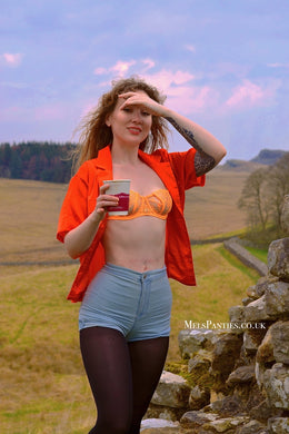 Melkimnylon with her shirt open and wearing used blue shorts and worn black tights with an orange bra 